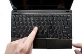 a finger pressing a key on a laptop keyboard