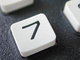 Lucky number 7 key on a white button on the keypad of a retro mobile phone with buttons in a close up view