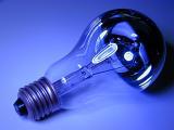 Electric light bulb with a screw mount lying on its side viewed in colorful blue light in a power and energy concept