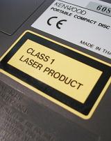 Yellow and black Class 1 laser product warning label on a Kenwood portable compact disc in compliance with international laws