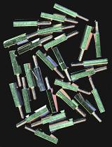 Top down view on scattered newly manufactured brass industrial metal bolts with greenish tint over black background