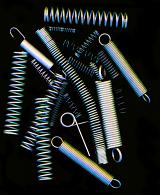 Collection of assorted metal steel springs or connectors on black viewed from overhead