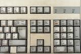 Old white computer keyboard with grungy dirty alphanumeric keys and functions viewed in a full frame background from above