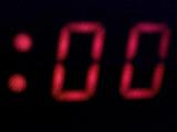 Blurred red digits of double zero on display of a clock or music player, glowing out of black background