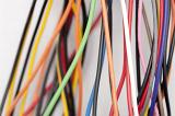 Jumble of colorful electric wires with plastic covering in the colors of the rainbow over a white background in an electronics and technology concept