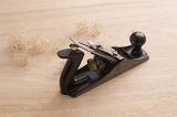 Carpenters plane tool and shavings on wooden surface viewed from high angle