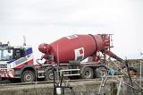 Large red cement mixer truck parked on a concrete wall or quay during construction or maintenance repairs
