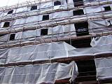 Scaffolding and plastic covers at a building site in a concept of commercial development and construction of high rise buildings