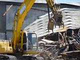 Heavy duty machinery clearing tangled metal after the demolition of a commercial building in a close up view on the jaws