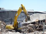 Demolishing an old or burnt down building with heavy duty equipment excavators, sorting metal elements with manipulator