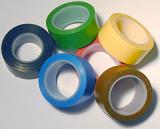 Pile of assorted rolls of electrical insulation tape in different colors over a white background viewed from above