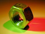 The steel nut in macro close-up with colorful shadow of green and red colors