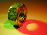 Close-up on steel nut hardware with colorful shadows of green and red lighting