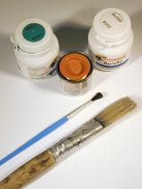Painting or decorating concept with paintbrushes of different sizes lying alongside small containers of paint viewed high angle