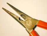 Pair of pliers with open jaws on white in a close up partial view from above