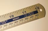 One foot ruler marked in inches and centimeters with weight units conversion rates printed as a reminder. Close-up cropped view