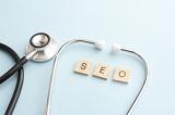 Search engine optimization concept with doctor stethoscope surrounding letters on wooden blocks over blue background