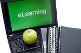 E-learning or distance learning concept with spiral bound notebooks and a fresh green apple lying on the keyboard of an open laptop with the word eLearning visible on the screen