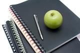 Black notebook binders piled, apple on top, concept of university of college education