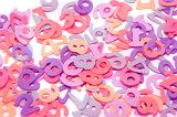 Random scattered numbers in shades of pink and purple on a tabletop for use in educating young children