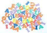 Collection of plastic vowels scattered randomly on a white surface for use in teaching children basic language and grammar and to read, write and spell
