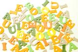 Scattered colorful vowels of the alphabet in yellow, green, cream and orange tones