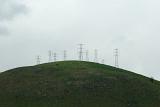 a line of power towers or pylons on top of a hill