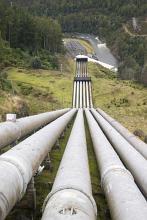 a series of pipes running down a steep valley piping water to a power station at the bottom