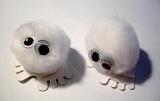 Overhead view of cute fluffy white puff balls with felt feet and glued on eyes