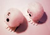 Pair of pink furry toys with large round eyes and four toes on feet from top view