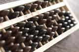 Traditional wooden abacus for manual computing in a close up view with focus to the counters at an oblique angle