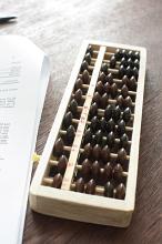 Abacus used for doing mathematical calculations beside form on dark wooden table