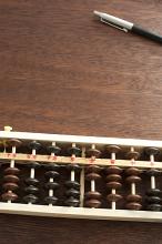 Pen and wooden abacus lying on a desk in a business accounting concept with copy space between