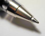 Close up view of the steel nib of a ballpoint pen over a white background with shadow and copy space