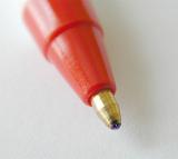 Extreme close up of roller ball pen tip with metal end and a red colored body