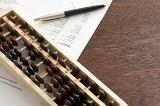 Narrow abacus on top of expense report with pen over dark brown wooden table with copy space