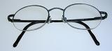Close up on pair of simple folded thin metal frame eyeglasses over gray background