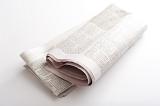 Folded newspaper on a white background lying diagonally with copy space either side