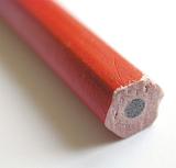 Back end of a red wooden pencil showing the graphite lead in a macro view with selective focus over white