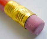 Extreme close up view of an eraser attached to end of a pencil with gold colored metal wrapped to keep it in place