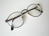 Pair or eyeglasses lying folded on a white background with copy space viewed high angle close up