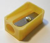 Simple yellow plastic pencil sharpener with a close up view on the blade at the top for school or office supplies