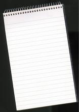 Top down view on blank unused spiral notepad with lines over black background for concept about business, education or journalism