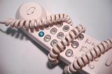 Single plastic touch tone generic white telephone handset wrapped up in spiral cord