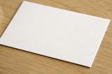 Plain white textured card on a wooden desk with copy space for your text viewed at an oblique angle