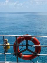 Onboard life buoy or preserver mounted on the rail of a boat with a view of the open ocean beyond