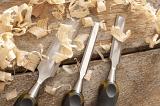 Three Wood Chisels on Wooden Background Surrounded by Wood Shaving Curls in Woodworking Concept Image