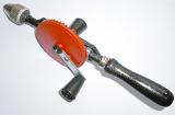 Old fashioned manual wood drill with a wheel and handle for handicraft work or carpentry lying diagonally on a white background