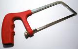 Junior hacksaw with fine-toothed saw and red plastic handle, close-up on gray