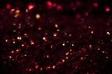 Background texture and pattern of the red highlights on glitter sparkling in the dark in a festive concept, full frame view